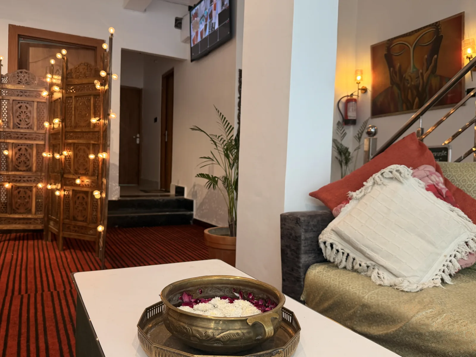 Flowers and cushions beside a warm wall lamp