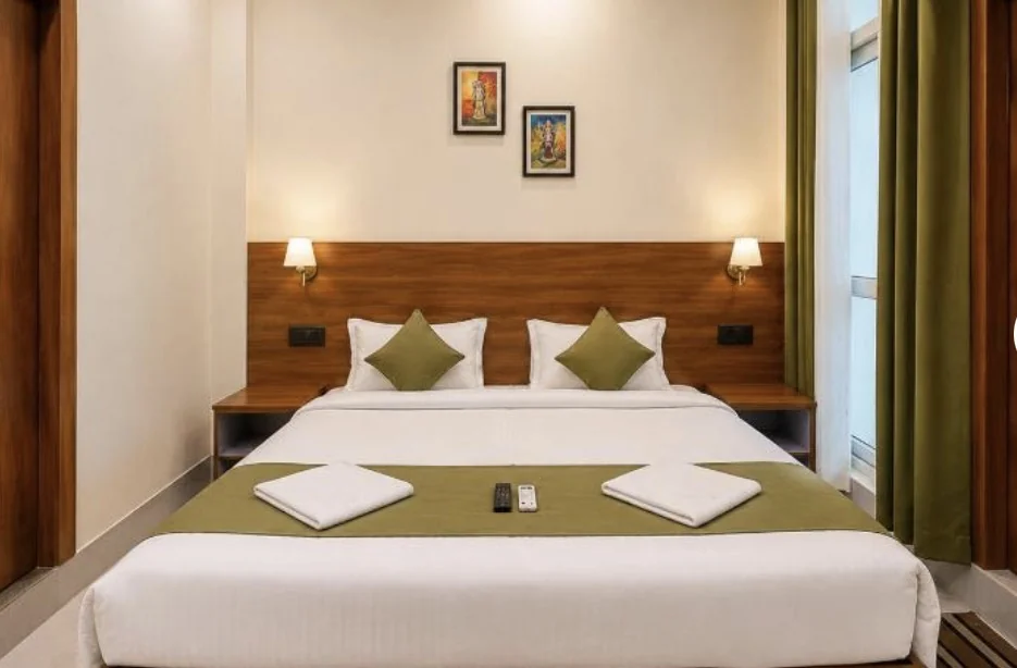 Double bed with warm bedside lamps and sage cushions at Sanskriti