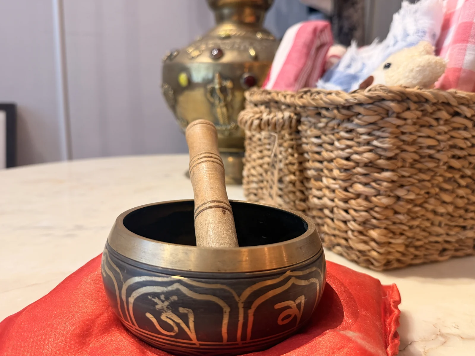 A singing bowl and wooden striker beside the boutique clothing rail
