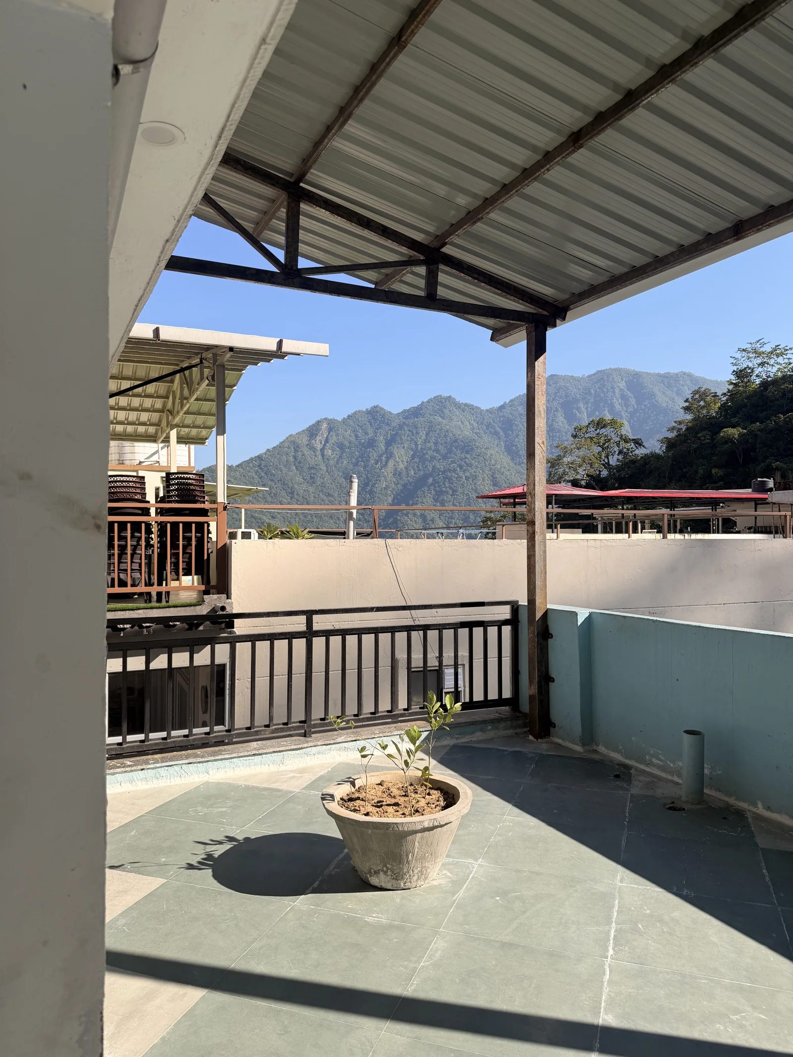 The covered Sanskriti rooftop terrace overlooking green mountains in Upper Tapovan